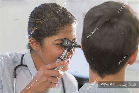 Female doctor using otoscope in ear of patient — medical exam, indian ethnicity - Stock Photo ...