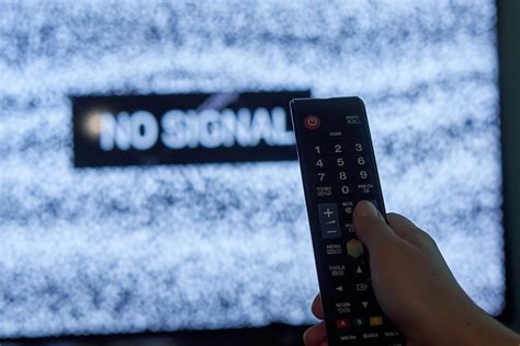 A hand holding tv remote over the TV display with 'No signal' sign - Creative Commons Bilder