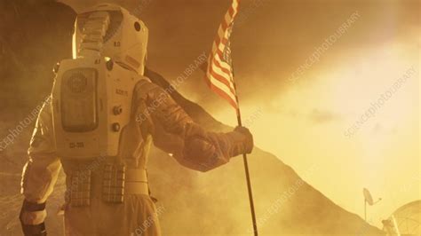 Astronaut on Mars walks with US flag - Stock Video Clip - K010/6108 - Science Photo Library