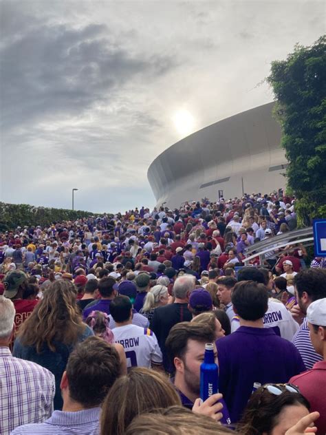 a large group of people standing in front of a building with a sky filled with clouds