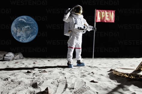 An astronaut on the moon saluting next to a flag with OPEN on it stock ...