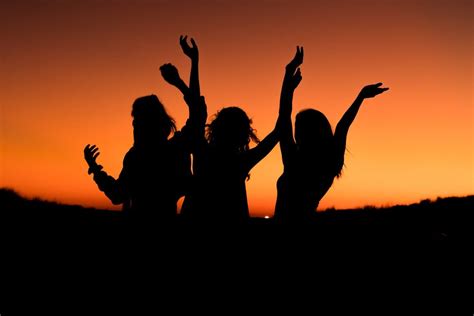 Silhouette of a group of friends celebrating in an orange sunset ...