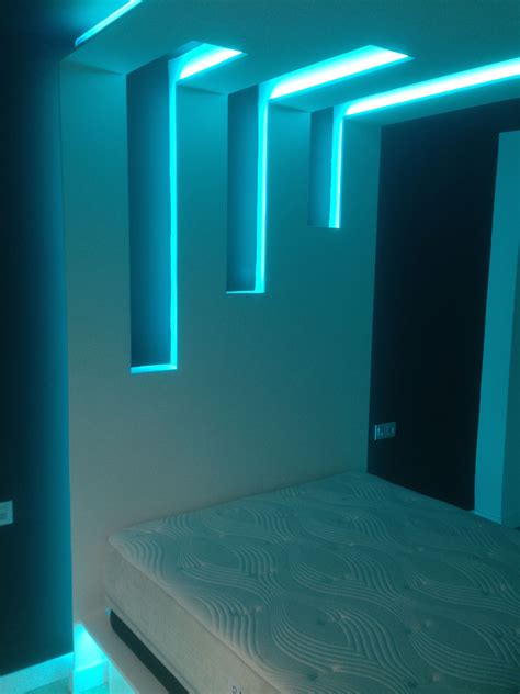 a bed in a room with blue lights on the ceiling and white mattresses ...