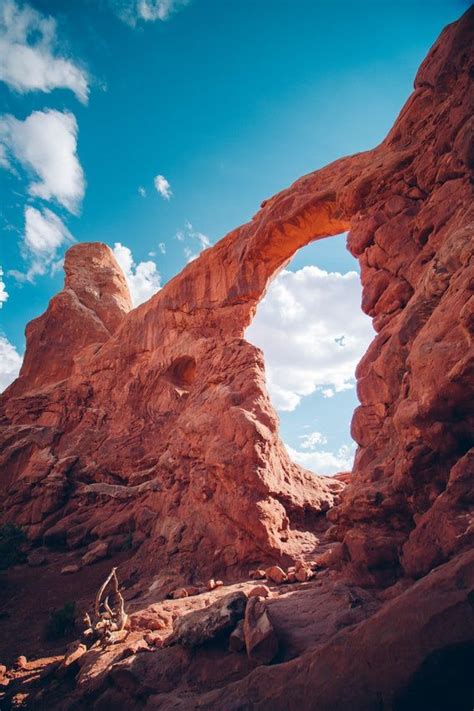 Unique orange rock formation forms an archway against a blue sky ...