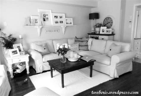 a black and white photo of a living room with couches, coffee table and pictures on the wall