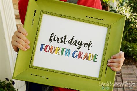 a person holding up a framed sign that says, first day of fourth grade