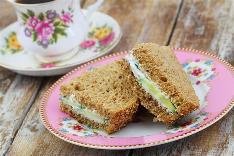 Brown bread sandwiches with cream cheese on colorful plate with cup of tea in vintage cup ...