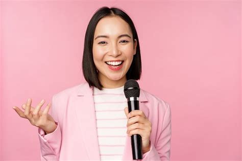 Image of enthusiastic asian businesswoman giving speech, talking with microphone, holding mic ...