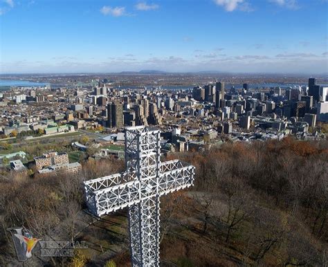 a large metal cross on top of a hill in front of a cityscape