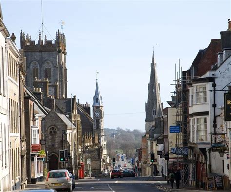 cars are driving down the street in front of buildings with steeples and spires