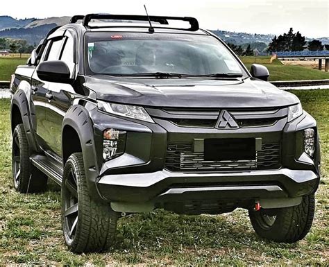 the front end of a black truck parked on top of grass