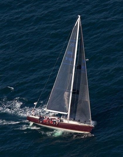 a sailboat sailing in the ocean with people on it's back end, viewed from above