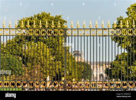 View of a heavy black wrought iron fence topped with golden spikes at the entrance of the ...