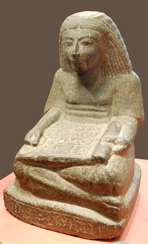 Ancient Egyptian statue, carved from diorite, of a seated scribe holding a papyrus scrol ...