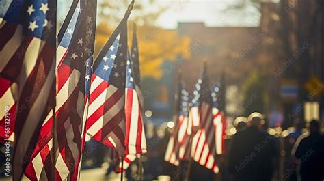 In mid-morning sunlight, a Veterans Day parade with American flags, and uniformed military ...