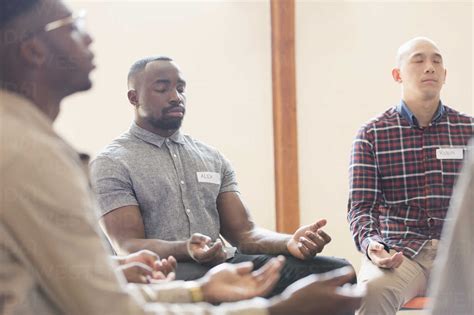 Men praying with eyes closed in prayer group stock photo