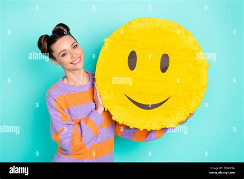 Portrait of satisfied young girl arms holding big paper emoji toothy smile isolated on blue ...