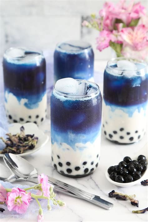 A layered drink with black tapioca pearls in the bottom swirls together ...