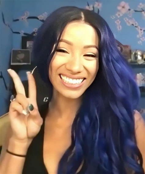 a woman with blue hair is making the peace sign