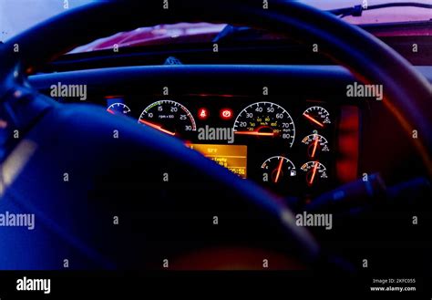 Modern American semi truck dashboard seen thru steering wheel with dash bezels light up, dark ...