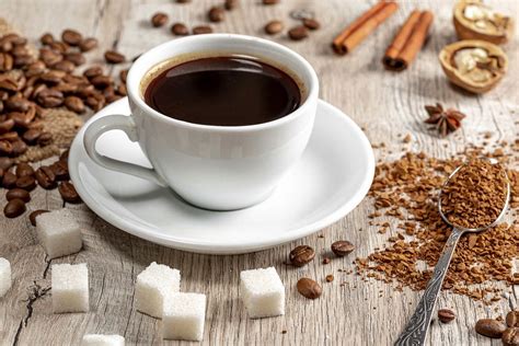 Coffee cup and beans on wooden table with spices, ground coffee and sugar cubes - Creative ...