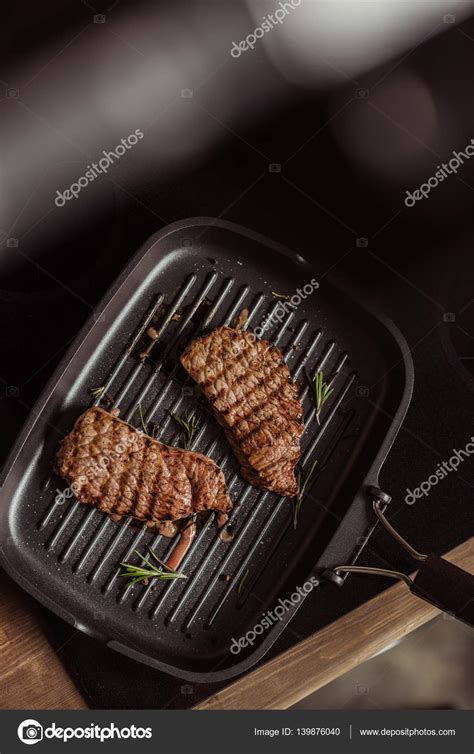 Grilled steaks in frying pan Stock Photo by ©ArturVerkhovetskiy 139876040