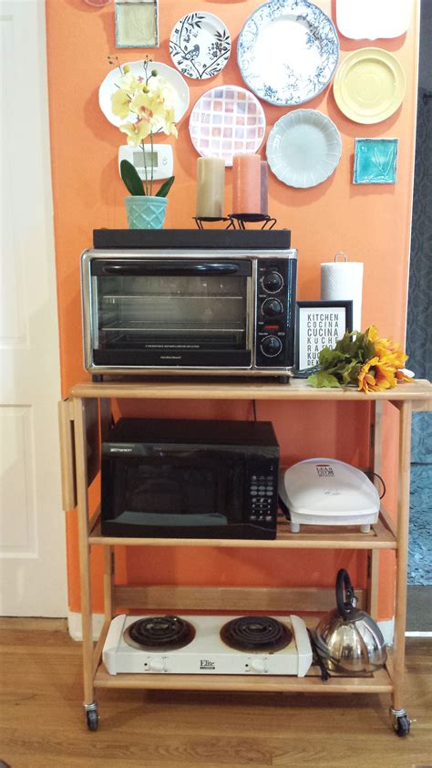 a microwave and toaster oven sitting on a shelf in front of an orange wall