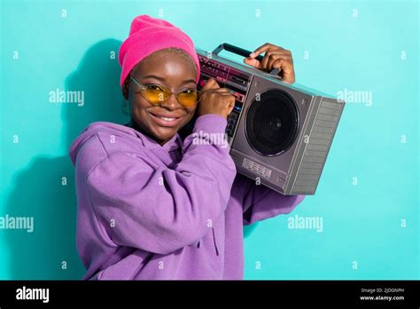 Portrait of attractive cheery girl carrying boombox listening hip hip isolated over bright teal ...