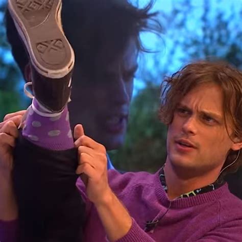 the man is holding up his shoe to show off it's purple color scheme