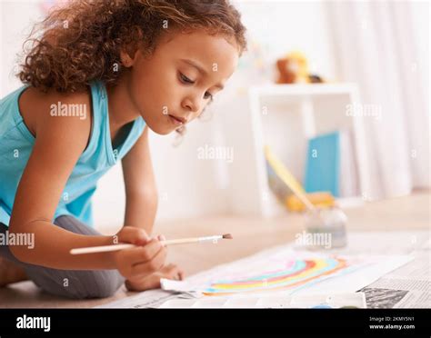 An artist in the making. a little girl lying on the floor and painting a picture Stock Photo - Alamy