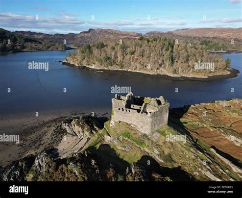 Aerial view of Tioram Castle perched atop a hill surrounded by green ...