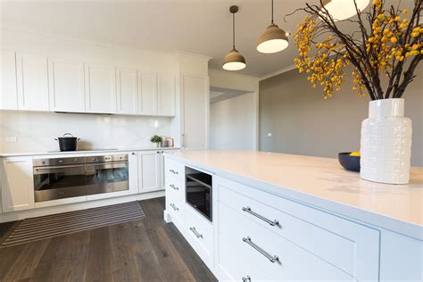 White shaker style vinyl wrap kitchen with stone bench tops and splash back