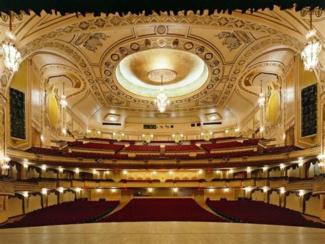 an empty auditorium with red seats and chandeliers