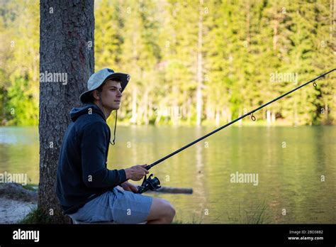 Man fishing at lake in a beautiful green nature Stock Photo - Alamy