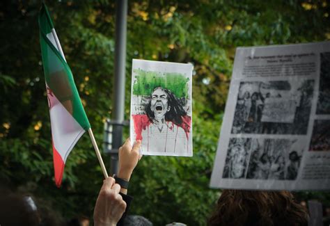 Hands Holding an Iranian Flag and a Protest Sign · Free Stock Photo