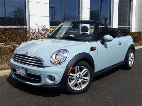 a light blue mini cooper convertible parked in front of a white building with large windows