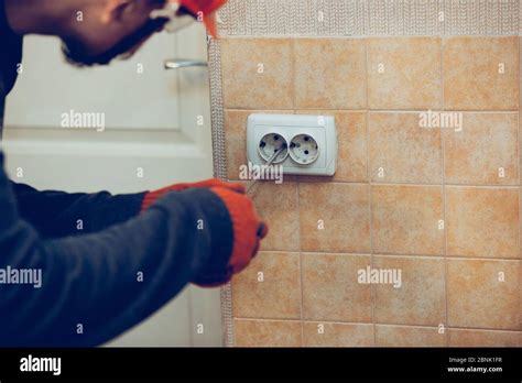 Electrician repair a wall socket at home or office. Closeup of man in ...