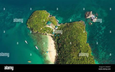 Tropical beach and turquoise water of the lagoon with tourists and boats, view from above ...