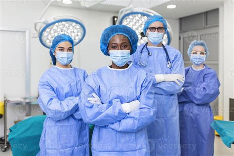 Group of medical surgeons wearing hospital scrubs in operating theatre. Portrait of successful ...