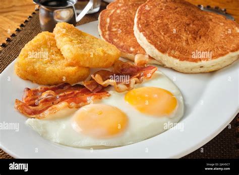 A closeup shot of an American breakfast with pancakes, eggs, hash brown ...