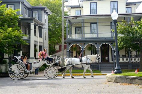 A horse drawn carriage walking by in the Cape May historic district ...