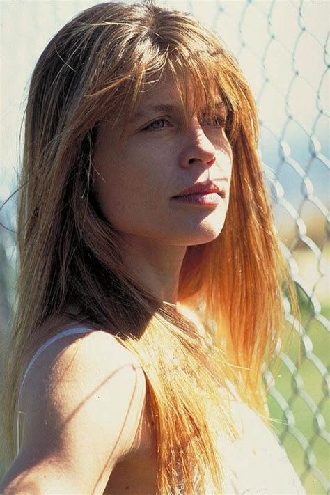 a woman with long hair standing next to a fence