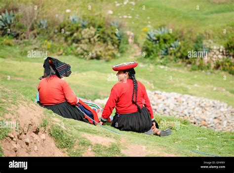 Dos mujeres indígenas andinos en su traje tradicional sentados en el césped a Sacsayhuaman ...