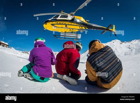 A group of skiers and snowboarders are dropped off by helicopter at the ...