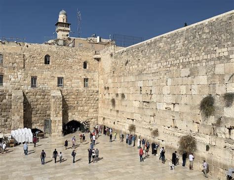 people are standing in front of an old stone wall