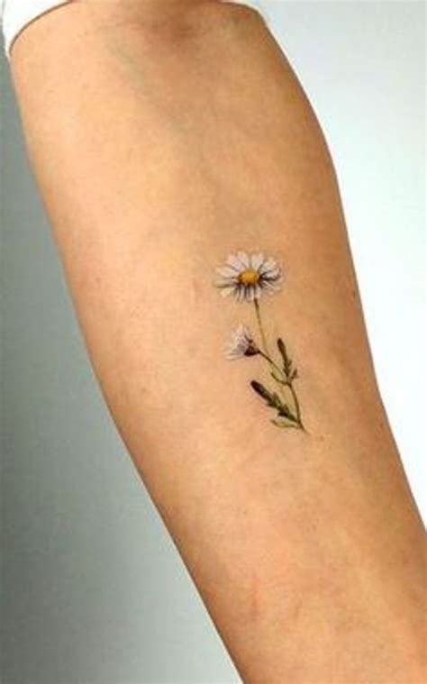 a small daisy tattoo on the arm