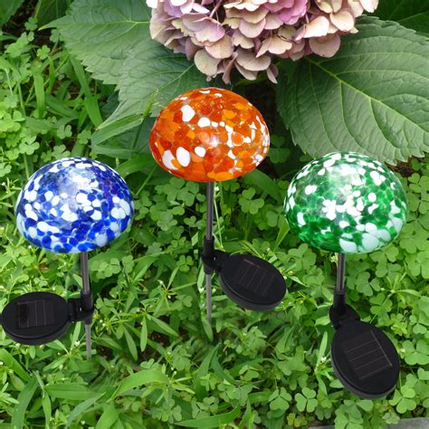 three colorful garden markers sitting on top of green grass next to a purple and pink flower