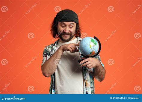 A Happy Male Traveler is Holding a Globe, a Map of the World, Choosing Where To Go. the Man ...
