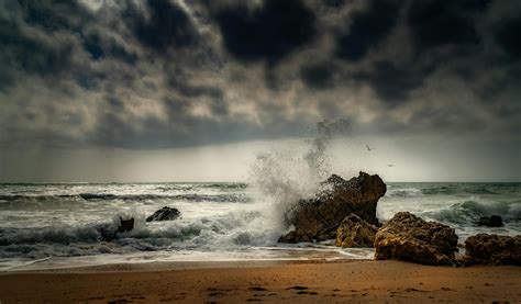 Ocean Waves Crashing on Brown Rock Formation Under Gray Clouds · Free Stock Photo