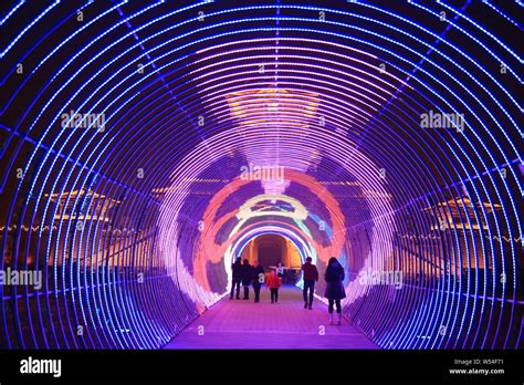 Visitors walk through a tunnel illuminated by colorful lights, which is called "Time Tunnel ...